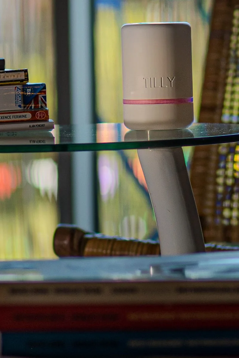 TILLY, tirelire connectée premium en ambiance cosy de fin de journée, halo lumineux violet — idée cadeau originale