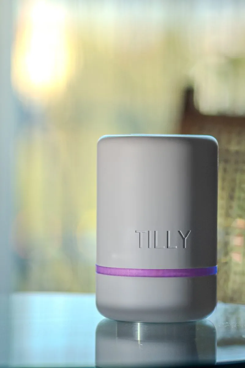 TILLY, tirelire connectée premium dans un salon familial, halo violet — outil d'éducation financière à la maison